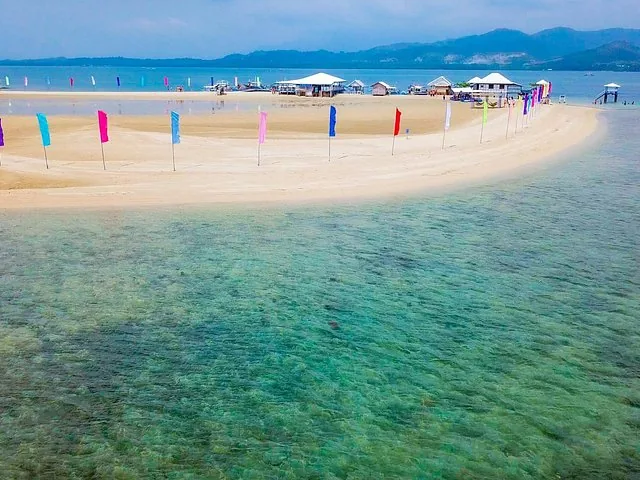 Sandstrand mit bunten Fahnen und klarem Wasser in der Honda Bay