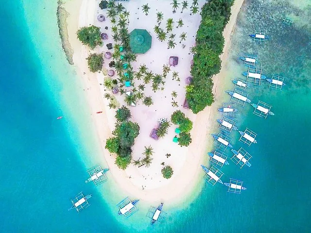 Aerial view of an island beach with palm trees and docked boats
