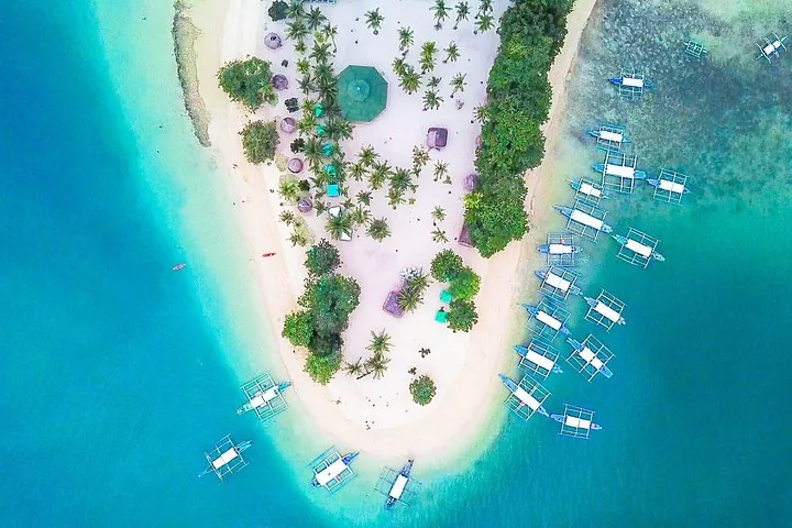 Luftaufnahme einer Sandinsel mit Palmen und angelegten Booten
